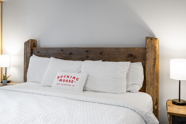 A neatly made bed with white bedding and a pillow with text. - The Bucking Moose (#08) Rabbit Room King Suite in West Yellowstone, 1 min to Yellowstone! (West Yellowstone)