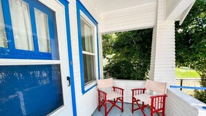 En veranda med en blå dörr, vita väggar och röda stolar.