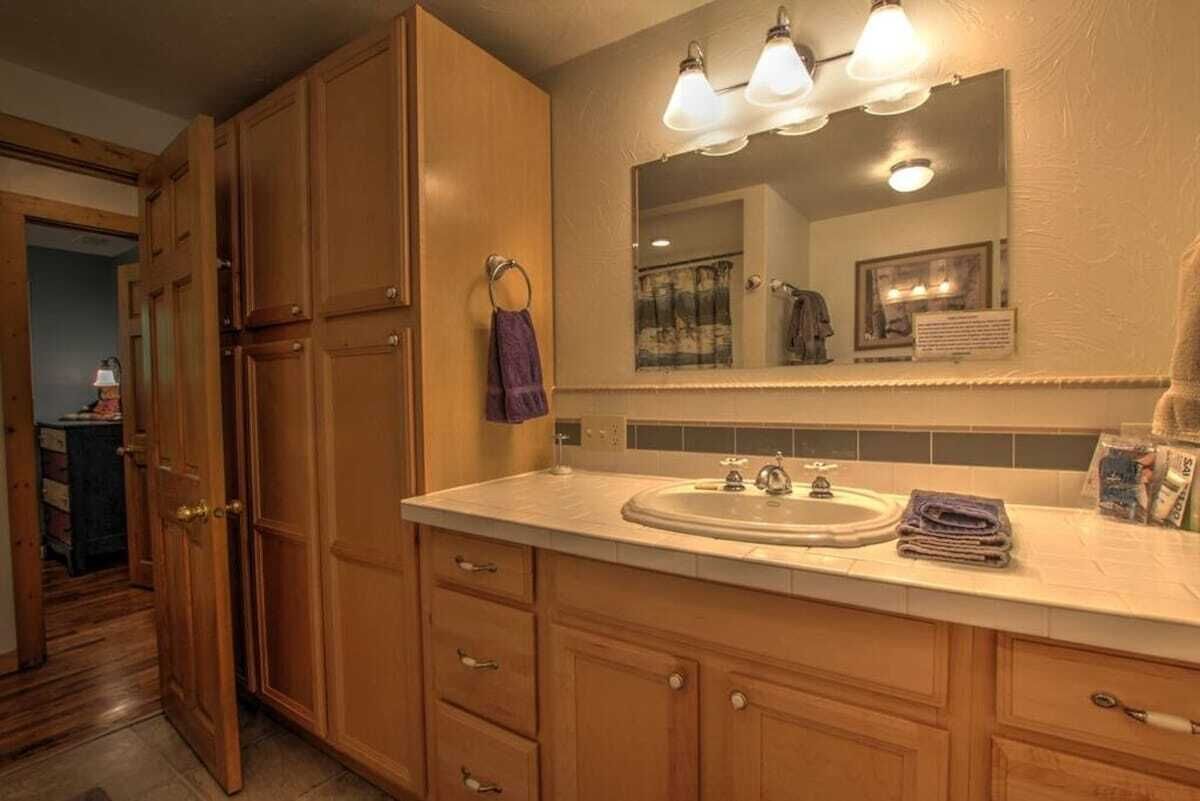 A bathroom with wooden cabinets, a sink, and a mirror with lights.