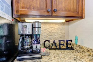 Una cocina con cafetera, tostadora y encimera que muestra la palabra 'CAFE'.
