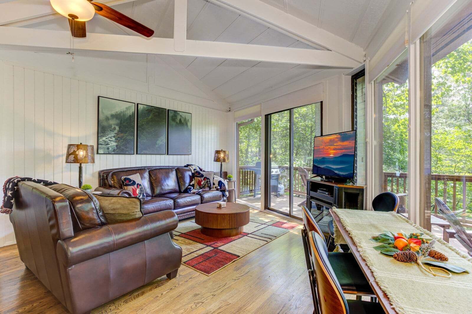 A spacious living room with a leather sofa, a coffee table, and a television on a stand.