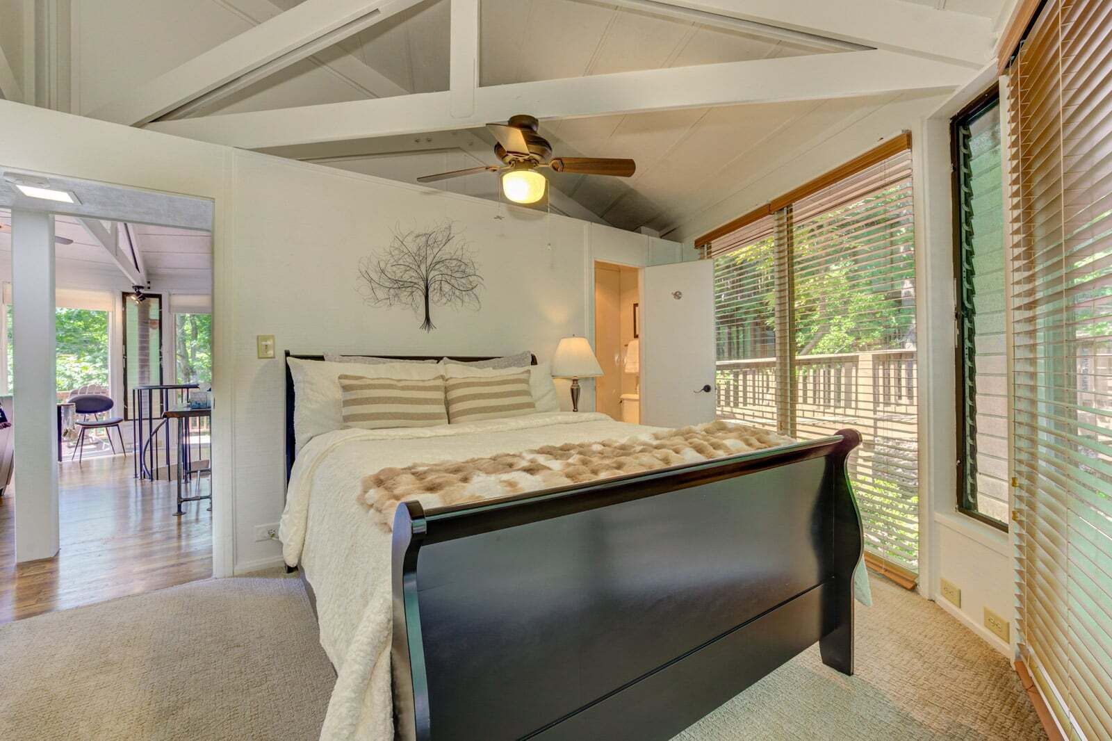 Une chambre à coucher avec un lit, un ventilateur de plafond, une fenêtre avec des stores et une vue sur l’extérieur.