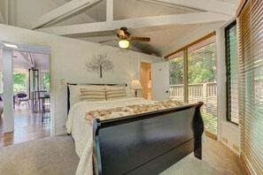 A bedroom with a bed, a ceiling fan, a window with blinds, and a view of the outdoors.