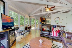 A spacious living room with a television, leather sofa, and a dining area with chairs.