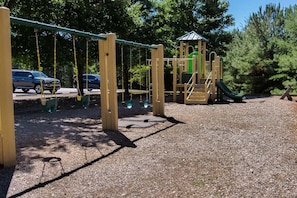 Un parque infantil con columpios, un tobogán y una estructura para escalar.
