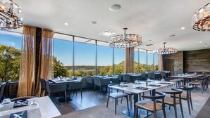 Un restaurant avec des tables et des chaises, de grandes fenêtres et de magnifiques lustres en cristal suspendus au plafond.