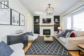 Una sala de estar moderna con chimenea, un sofá, una mesa de centro y un televisor montado en la pared.