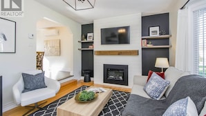A modern living room with a fireplace, a flat-screen TV, and a cozy seating area. - Cozy & Spacious 2BR home in a quiet neighborhood near shopping center (Lower Sackville)