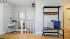 A staircase with white railings and a wooden handrail, leading to a landing with a white console table and a potted plant. - Cozy & Spacious 2BR home in a quiet neighborhood near shopping center (Lower Sackville)