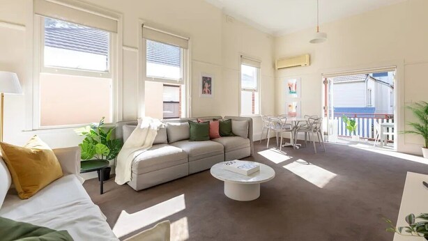 A spacious living room with a sofa, coffee table, and a balcony with a railing. - Oversized Artdeco Apartment w 4m high ceilings (Glebe)