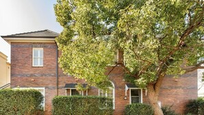 A two-story brick building with a large tree in front. - Oversized Artdeco Apartment w 4m high ceilings (Glebe)