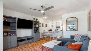 A modern living room with a grey sofa, a white coffee table, a flat-screen TV, and a ceiling fan. - 08 Lodge, Downtown, AC, Ground Floor, Hood River! (Hood River)