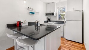 A modern kitchen with a black countertop, white cabinets, a built-in microwave, and a refrigerator. - 08 Lodge, Downtown, AC, Ground Floor, Hood River! (Hood River)