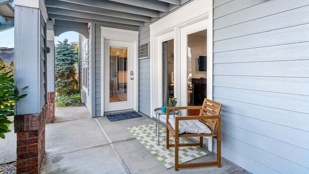A covered porch with a wooden bench, a door leading to a room, and a small table with a blue cup. - 08 Lodge, Downtown, AC, Ground Floor, Hood River! (Hood River)