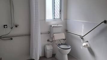 A modern bathroom with a shower, toilet, and window.