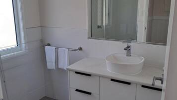 Ein Badezimmer mit einem weißen Waschbecken, einem Spiegel und einem Fenster.