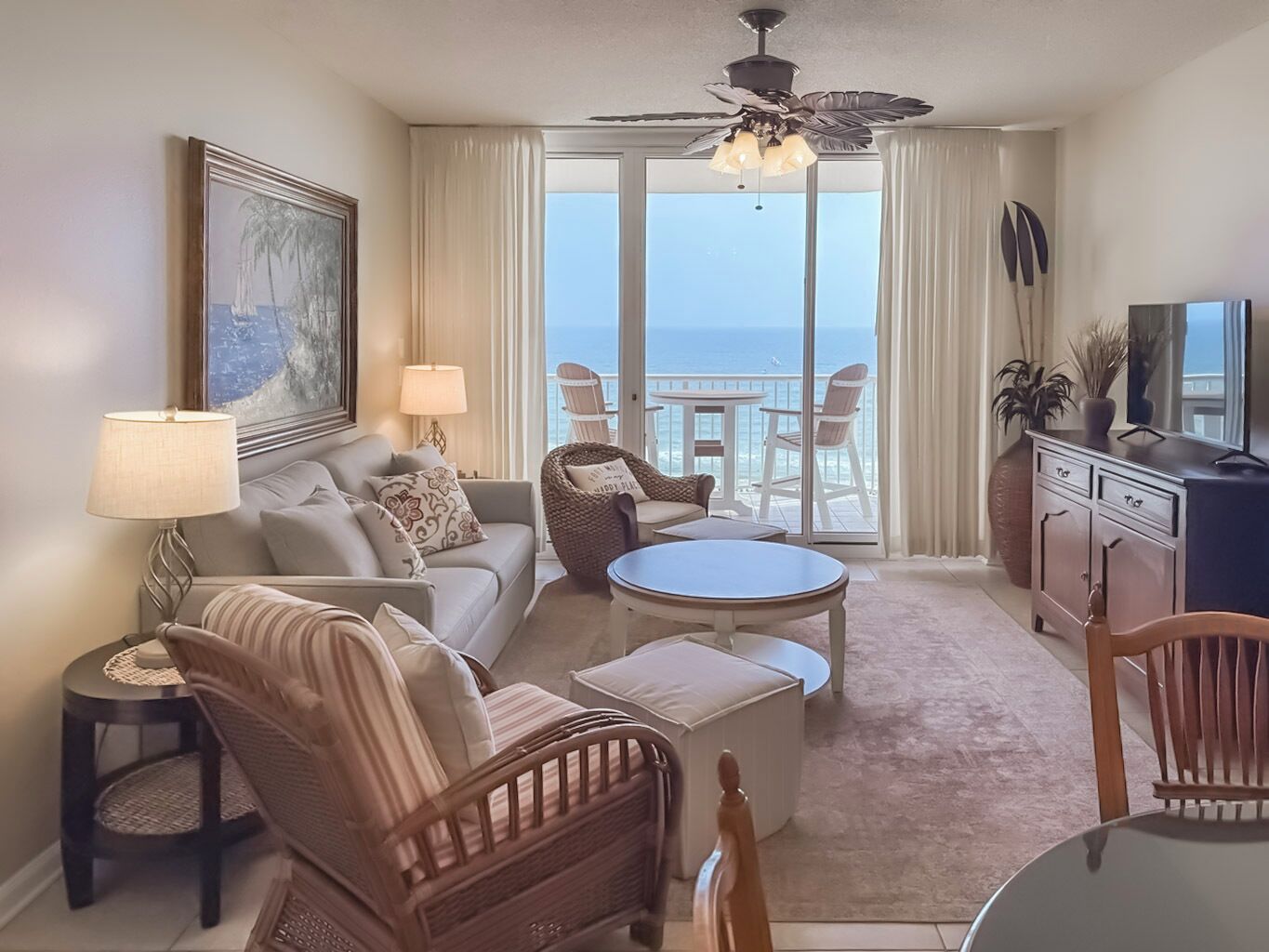Una sala de estar con sofá, sillas, mesa de centro, televisor y balcón con vistas.