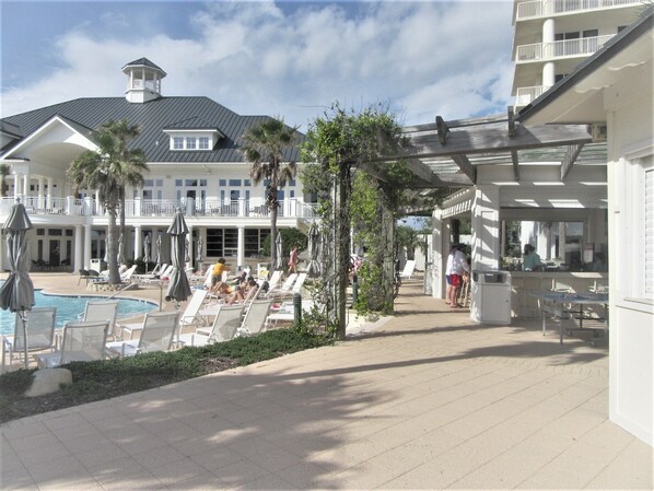 Zwembad van een resort met ligbedden, parasols en een gebouw met een balkon.