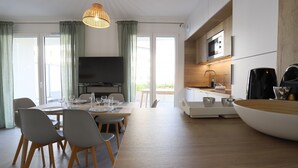 A modern kitchen with a microwave, coffee machine, and a dining area with a table and chairs. - Reflet du Parmelan Annecy (Annecy)