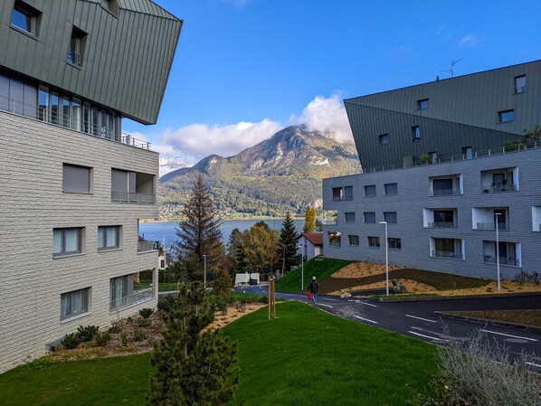 A modern building with a stone facade, a road in front, and a mountain in the background. - Reflet du Parmelan Annecy (Annecy)