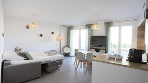 A modern hotel room with a bed, a dining area, and a TV. - Reflet du Parmelan Annecy (Annecy)