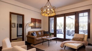Ein Wohnzimmer mit braunem Ledersofa, beigen Sesseln, einem Couchtisch und einer Deckenleuchte.
