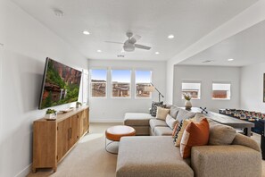 A modern living room with a sofa, ottoman, and a foosball table.
