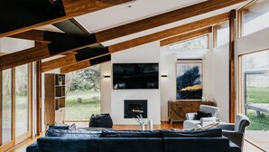 A modern living room with a fireplace, large windows, and a view of the outdoors.