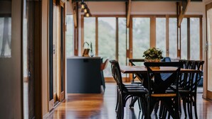 A dining area with wooden flooring, a table with chairs, and a potted plant on the table.