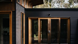 A modern building with a large wooden door and a window with horizontal blinds.