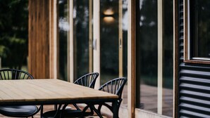 A wooden table with four chairs in a room with large glass doors and windows.