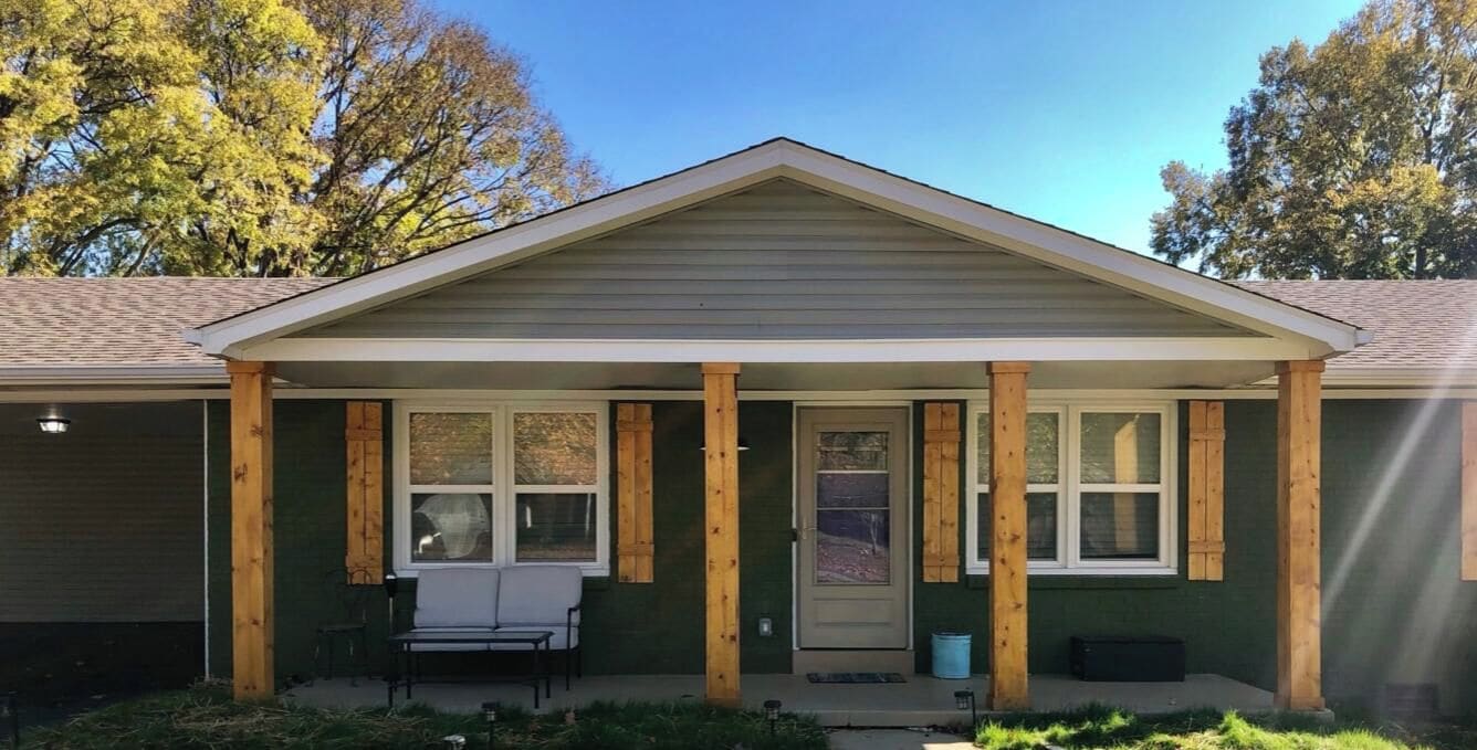 Een huis met twee verdiepingen, een veranda, een garage en een overdekte entree.