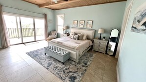 A bedroom with a large bed, a ceiling fan, a nightstand with a lamp, and a sliding glass door leading to an outdoor area. - Scenic Lake View Home with Pool & Hot Tub (Bandera)