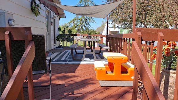 A wooden deck with outdoor furniture, including a table and benches, and a pergola providing shade.