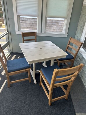 A small outdoor patio with a white table and four wooden chairs with blue cushions. - Adorable Beach house with lots of outdoor space and steps to Long Beach!  (Rockport)