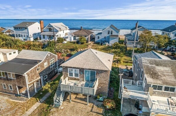 A coastal residential area with houses featuring front porches and a view of the ocean. - Adorable Beach house with lots of outdoor space and steps to Long Beach!  (Rockport)