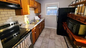 A kitchen with wooden cabinets, a stainless steel sink, a black refrigerator, and a microwave. - Central Stay! Near UK/Downtown/Campus. (Lexington)