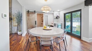 A modern kitchen with a round dining table, clear chairs, and a pendant light. - High-end home w/ fireplace, gourmet kitchen, sauna, game rm/ large yard/fire pit (Mason)