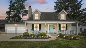 A two-story house with a porch, a garage, and a well-maintained front yard. - High-end home w/ fireplace, gourmet kitchen, sauna, game rm/ large yard/fire pit (Mason)