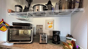 Uma cozinha com forno embutido, torradeira, cafeteira e diversos utensílios de cozinha nas prateleiras.