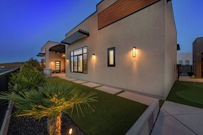 A modern house with a patio, a covered seating area, and a well-maintained lawn. - Paradise Retreat at Copper Rock! (Hurricane)