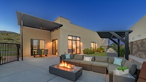 Eine moderne Außenpatio mit Feuerstelle, Sitzgelegenheiten und einer Pergola.