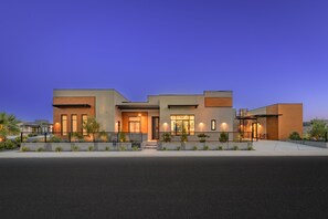 A modern two-story house with a flat roof, large windows, and a well-lit entrance. - Paradise Retreat at Copper Rock! (Hurricane)