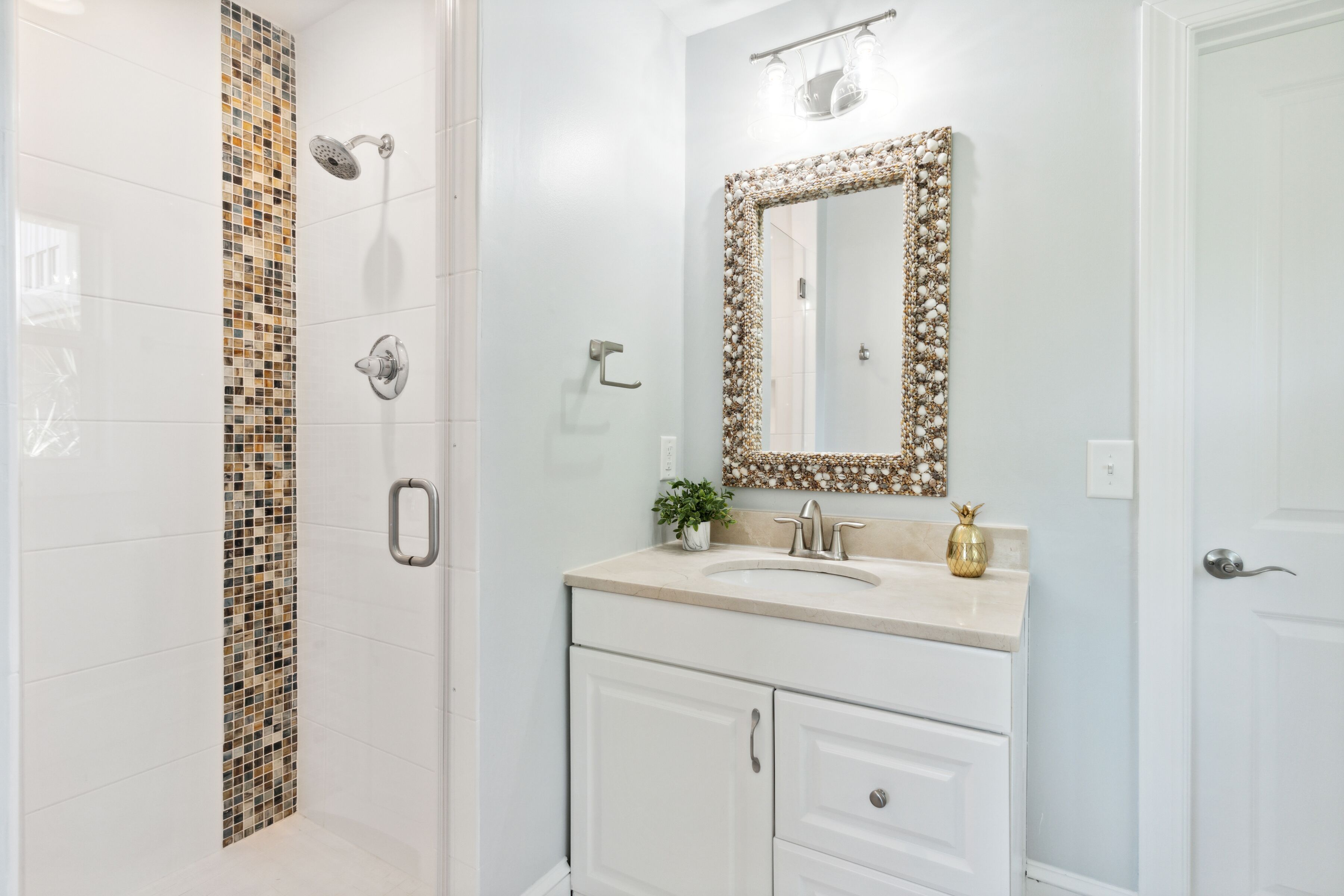 A bathroom with a shower, a sink with a decorative mirror, and a cabinet.