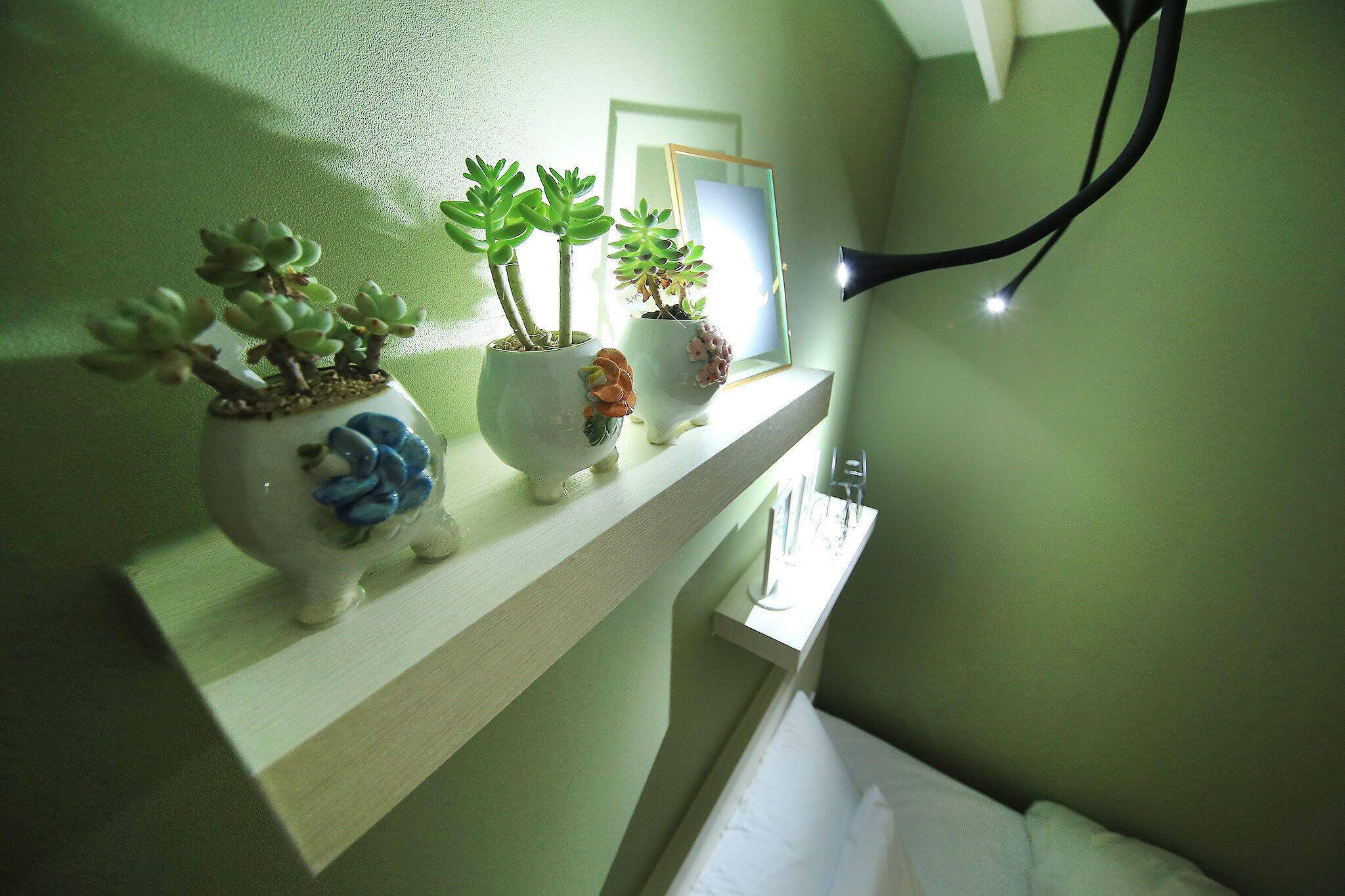 A bathroom with a shelf holding three potted plants.