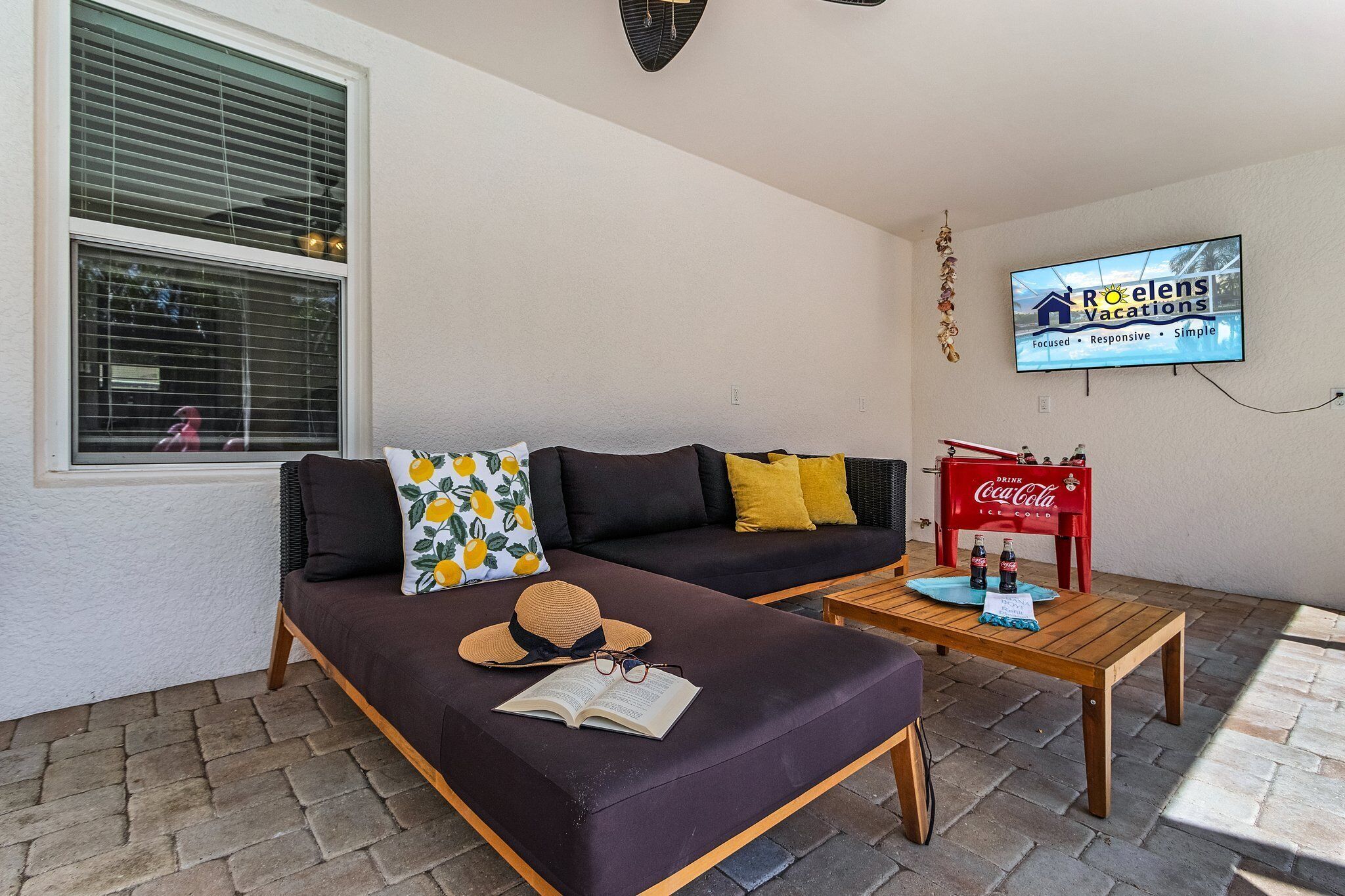 Een gezellig buiten zitgedeelte met een bank, een kleine tafel en een aan de muur bevestigde televisie.