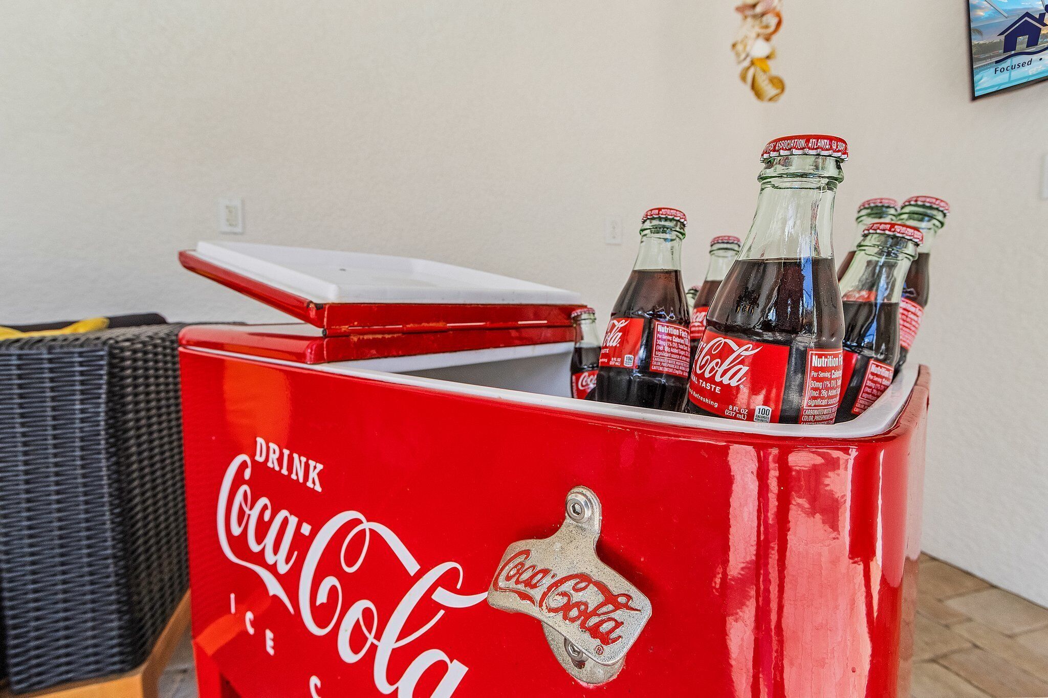 A red Coca-Cola branded cooler with bottles inside, placed on a wooden surface.