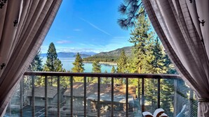 Un balcon avec vue sur un lac, des arbres et des montagnes.