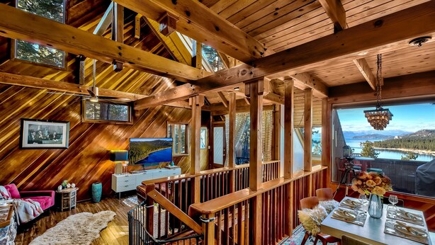 Un intérieur en bois comprenant un coin repas, un escalier et une vue sur un lac.