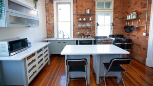 A compact kitchen with white cabinetry, a microwave, a stove, and a sink.